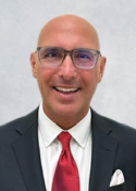 Smiling person with bald head wearing glasses and a suit and tie