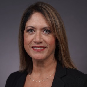 Angela Becerra wearing a black blazer with shoulder length brown hair 