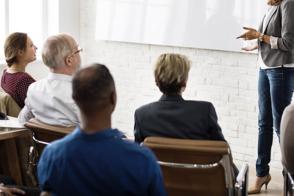 A group of adults sitting in chairs listening to a speaker