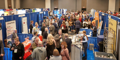 Large amount of people milling about in an exhibit hall