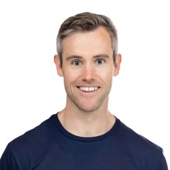 smiling person with short light brown hair wearing a blue tshirt