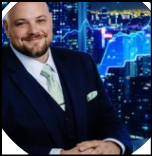 Smiling person with facial hair in a business suit wearing a green tie and pocket square