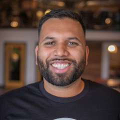 Smiling person with short dark hair pushed to the side and a close cropped beard.