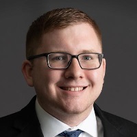 Smiling person with rectangle glasses wearing a classic suit and tie