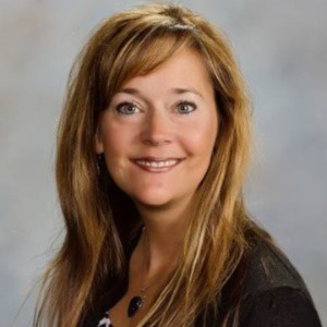 Person with long golden hair looking directly at the camera with a smile.