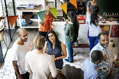 Group of people milling about with celebratory banner overhead