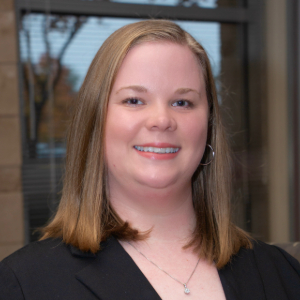 Person with shoulder length light brown hair wearing a black blazer. 