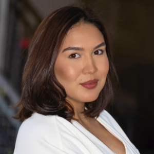 Person with shoulder length brown hair wearing red lipstick and a white blouse