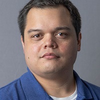 Person with short dark hair wearing a blue polo shirt
