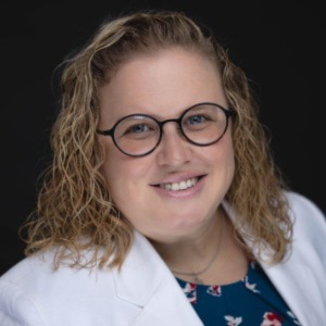 Sarah Bowman with white blazer and rounded black glasses